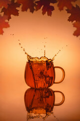 Creative Splash Photography In Transparent Mug With Tea, Autumn Leaves, Autumn Concept, Warm Colors, with copy space