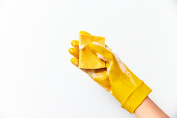 Person in yellow rubber gloves holding a sponge with another yellow sponge on top of it on a white background