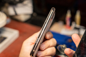 Smartphone with broken glass in a phone repair service during a busy afternoon