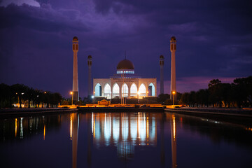 A large white Mosque with The water is calm and reflects the twilight sky, Central Mosque Songkhla,...