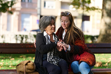 Embracing Generations: A Daughter's Love and Support for Her Senior Mother on a Sunny Day in the Park