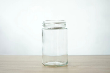 An empty clear glass is placed on a wooden patterned table isolated on a white background