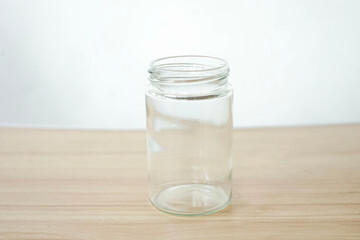An empty clear glass is placed on a wooden patterned table isolated on a white background