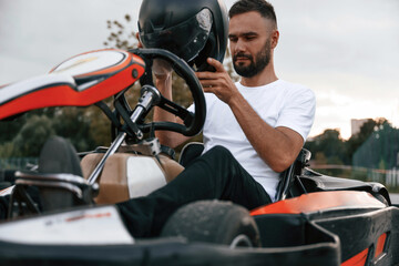 Wearing the safety helmet. Man is outdoors, kart racing conception
