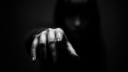 The hand extends forward against a dark background, creating an intense and mysterious atmosphere that draws the viewer's attention and evokes curiosity