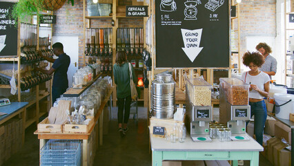 Shoppers Looking At Products In Busy Sustainable Plastic Free Grocery Store