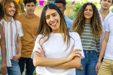 Young woman smiling with crossed arms and friends in the background