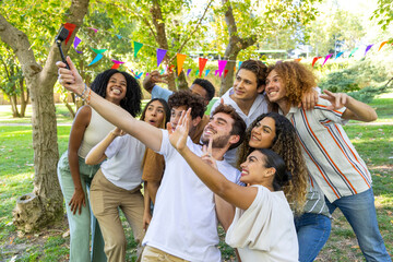 Group of friends taking selfie in park with colorful flags