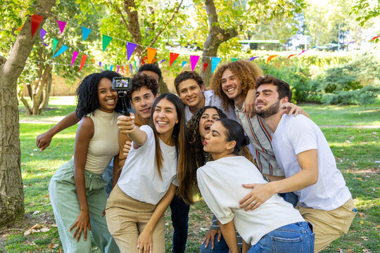Group of friends taking selfie in park using selfie stick