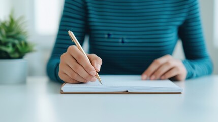 Fototapeta premium A close-up of a person writing in a notebook, showcasing their focused hand movement with a pencil against a softly blurred background.