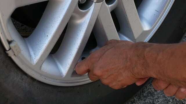 close up to car's tire while driver inflating car tire in sunny daytime. Hand holding hose with air pressure gauge and filling up car's tire with nitrogen air.mechanic checking tire pressure.