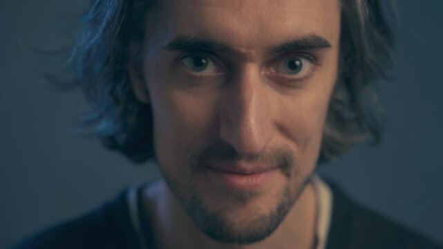 young man with long hair, large expressive eyes, European appearance, smiles, winks with his right eye, becomes serious twice