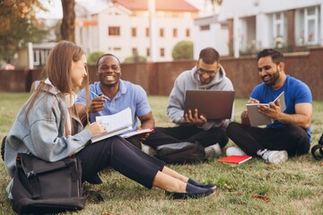 Fototapeta na wymiar Group of Diverse Students Studying Together Outdoors on Campus While Smiling and Engaging in Teamwork