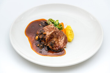 Grilled beef tenderloin with Demi glace sauce with grilled vegetables on a white porcelain plate