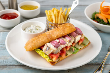 Grilled fish sandwich with red onion. With french fries and sauce