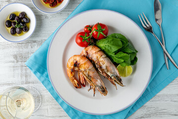Red prawns or tiger prawns on a white plate with greens and tomatoes. Tiger shrimps