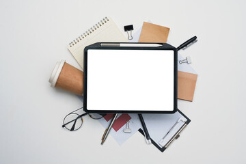Digital tablet with blank display and variety of office supplies on white table. Flat lay, Top view