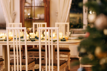 A dining table covered with candles and Christmas decor. Empty cutlery