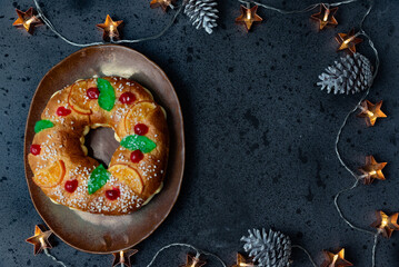 Traditional Roscón de Reyes surrounded by Christmas lights.