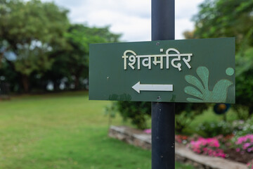 Arrow Road Sign in Hindi devanagri Shiv Mandir in Green Background