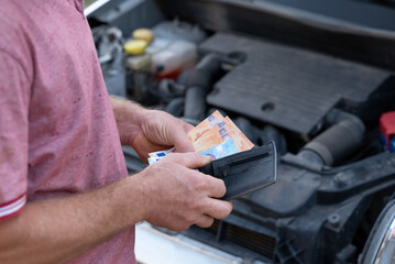 Service worker counting earned money and putting them to his wallet. Individual car mechanic fixing cars and earns money for his work