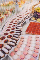 Candy bar on the holiday made in pink colors. In the foreground is a delicious macarons dessert on food stand. Different kinds of baked sweets on a buffet. 