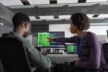 Coworkers discussing computer program in office