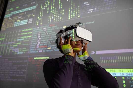 Coder testing VR headset with coding on large presentation screen 