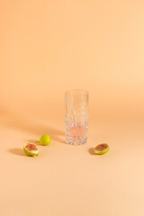 Cryistal cocktail glass and yellow fig slices on a sunny day. Summer drink and fruits on orange background.