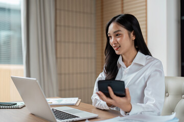 Professional Woman Working from Home Office with Laptop and Smartphone, Smiling and Engaged in Business Tasks