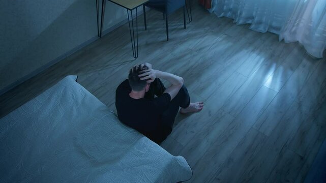 Lonely man sitting on the floor in the room in a state of depression. Concept of mental health, problems and stress. Psychological disorder.