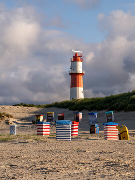Electric lighthouse with striped beach chairs on the coast of the Island of Borkum, Lower Saxony, Germany.
