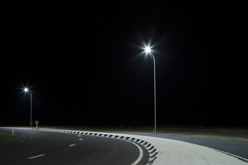Curved road at night illuminated by streetlights in the Netherlands.
