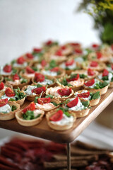 Sandwiches with cheese greens and tomatoes on a wooden tray.