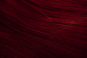 Dark red hair close-up as a background. Women's long brown hair. Beautifully styled wavy shiny curls. Coloring hair with bright shades. Hairdressing procedures, extension.