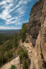 landscape of Rocky Cliffside Path Overlooking Lush Green Valley with Expansive Sky View