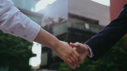 Businesspeople shake hands standing on street in city downtown