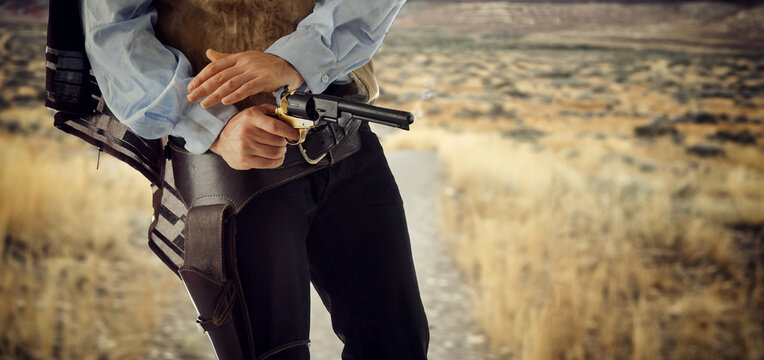 Cowboy posing with gun in holster at high noon western style duel