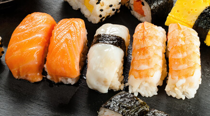 Variety of delicious nigiri sushi pieces resting on black slate