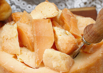Sliced cheese wheel with knife resting on cutting board