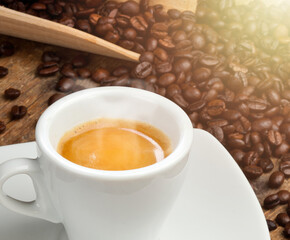 Steaming espresso coffee in white cup with coffee beans background