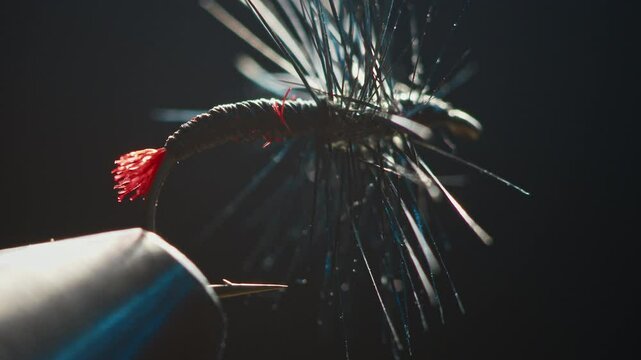 Handmade fishing fly in the vice on the solid studio background