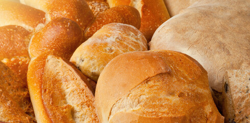 Assortment of freshly baked bread loaves is awaiting customers on the shelves of a bakery