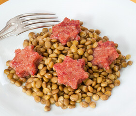 Stewed lentils with star shaped cotechino served on a plate