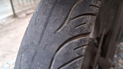 Front tire of motorbike,a worn tire tread and a little cracked, must be replaced immediately