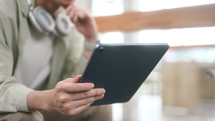 Close-up of Smart Young adult man digital reading on tablet in a cafe, Selective focus on hands