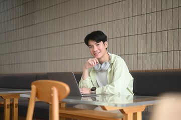 A freelance man enjoys the relaxed in a cafe, working on his laptop, embodying the flexibility of freelance life, the modern lifestyle, where work can be done comfortably from any location