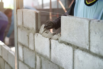 masonry worker make concrete wall by cement block and plaster at construction site                   