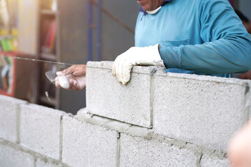 masonry worker make concrete wall by cement block and plaster at construction site                   