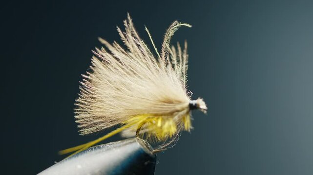 Handmade fishing fly in the vice on the solid studio background